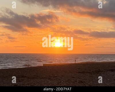 Hastings, East Sussex, UK - 03.12.2020   Sonnenuntergang über dem Meer am Strand von Hastings beliebter Touristenstrand mit Kieselsteinen und Groynes Stockfoto