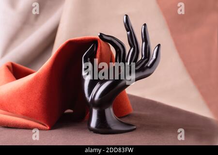 Schwarze Kunststoff Schaufensterpuppen Hand Holding Stück Velours Stoff. Fabric-Hintergrund Stockfoto