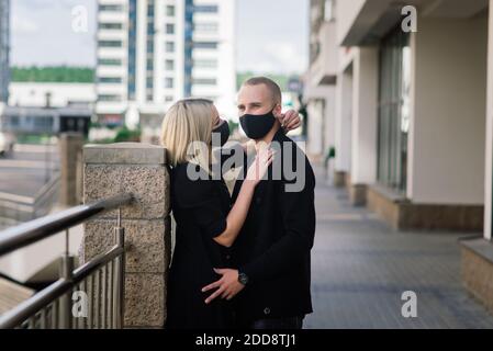 Paar tragen modische Schutzmasken, zu Fuß in leeren Straßen der Stadt während der Quarantäne. Stockfoto