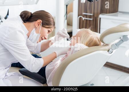 Eine junge Zahnärztin, die eine gründliche Untersuchung der Zähne ihres Patienten durchführt. Stockfoto