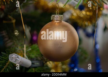 Makrofoto von einer goldenen Weihnachtskugel, die am Weihnachtsbaum hängt. Stockfoto