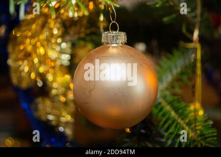 Makrofoto von einer goldenen Weihnachtskugel, die am Weihnachtsbaum hängt. Stockfoto