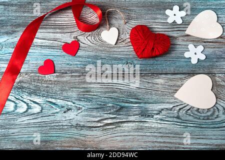 Rote und weiße Herzen und Band auf einem grau-blauen Hintergrund aus Holz. Stockfoto