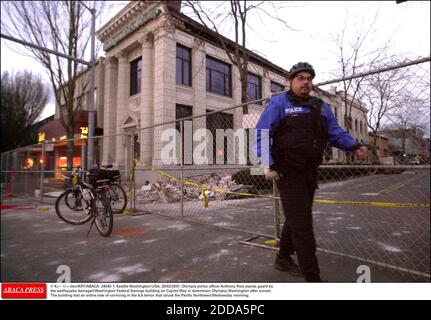KEIN FILM, KEIN VIDEO, KEIN FERNSEHEN, KEIN DOKUMENTARFILM - © KARL MONDON/KRT/ABACA. 24045-1. Seattle-Washington-USA, 28/02/2001. Olympia Polizeioffizier Anthony Rios steht Wache durch das Erdbeben-beschädigte Washington Federal Savings Gebäude auf dem Capitol Way in der Innenstadt von Olympia, Washington nach Sonnenuntergang. Das Gebäude Stockfoto