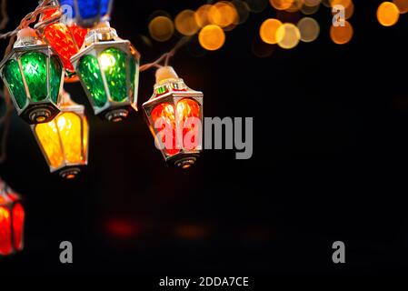 Glühende Weihnachtslichter in schwarzer Nacht. Bunte Feen weihnachtslichter mit Vintage Laterne förmigen Lampen. Stockfoto