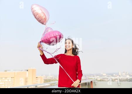 Frau, die Ballon anschaut, während sie auf der Terrasse steht Der Himmel ist klar Stockfoto