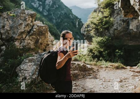 Lächelnde Wandererin, die beim Wandern Selfie über das Smartphone nimmt Stockfoto