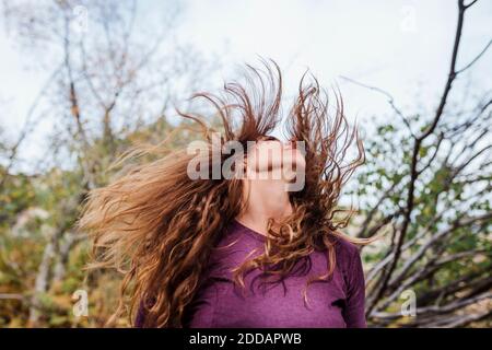 Sorglose Frau, die Haare wirft, während sie im Wald in La Pedriza, Madrid, Spanien steht Stockfoto
