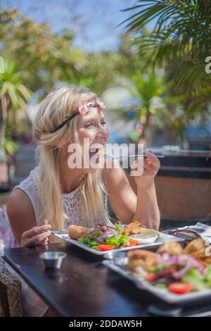 Junge Frau beim Mittagessen, während sie im Restaurant in der Stadt sitzt Stockfoto