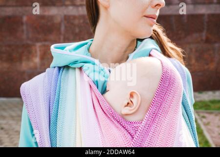 Mittelteil Mutter trägt Baby in Decke gewickelt stehen auf sonnig Tag Stockfoto