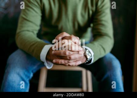 Mann mit Händen zusammengeklemmt sitzt auf dem Tisch zu Hause Stockfoto