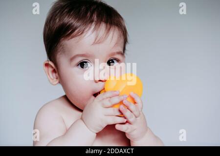 Niedlichen kleinen Jungen setzen Spielzeug in seinem Mund während sitzen Zu Hause Stockfoto