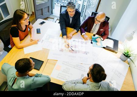 High-Angle-Ansicht der Geschäftsleute und Geschäftsfrauen diskutieren über Blaupause Auf dem Tisch im Büro Stockfoto
