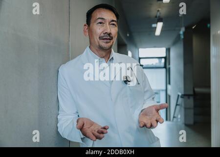 Wissenschaftler blicken weg, während er sich an der Wand am Klinikkorridor lehnt Stockfoto