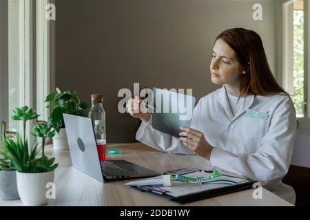 Zahnärztin erklärt dem Patienten Röntgenstrahlen durch Videoanruf Laptop zu Hause Stockfoto