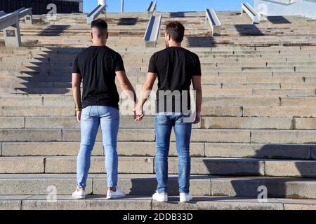 Homosexuelles Paar, das bei Sonnenschein die Hände hält, während es auf der Treppe steht Tag Stockfoto