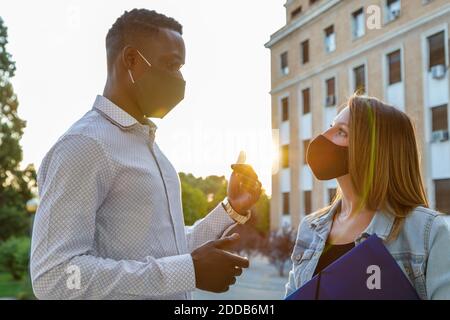 Männliche und weibliche Schüler tragen eine schützende Gesichtsmaske während der Diskussion Auf dem Universitätsgelände Stockfoto