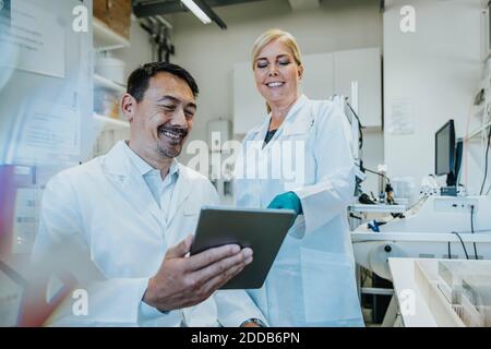Wissenschaftler lächeln, während Sie digitale Tablette im Labor verwenden Stockfoto