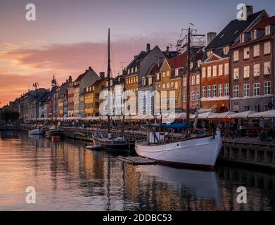 Dänemark, Kopenhagen, Boote, die entlang Nyhavn Promenade in der Abenddämmerung mit Reihe von historischen Stadthäusern im Hintergrund festgemacht Stockfoto