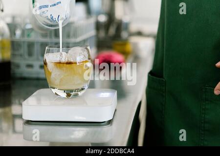 Der Barista steht während er Milch in die Kaffeetasse gießt Küchenwaage im Coffee Shop Stockfoto