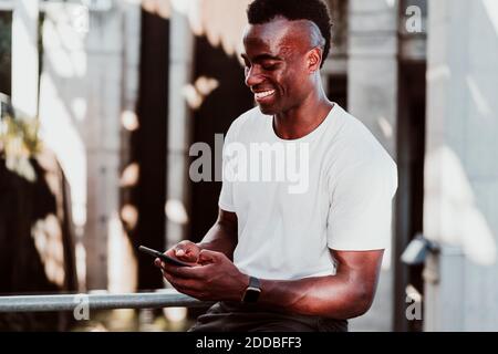 Lächelnder Sportler SMS auf Smartphone sitzen Stockfoto