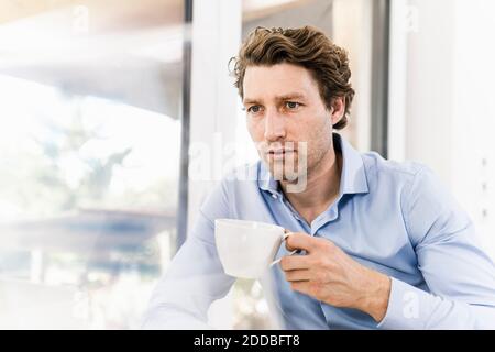 Ein Mann mittleren Erwachsenen trinkt Kaffee, während er im Büro sitzt Stockfoto