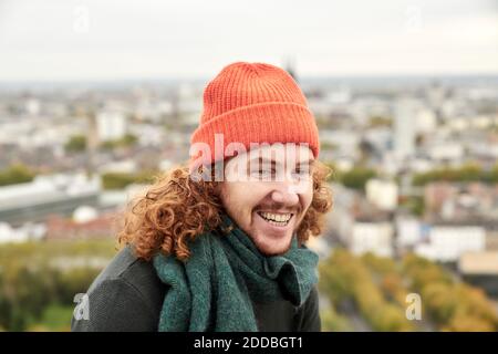 Fröhlicher Rotschopf Mann trägt Strickmütze gegen Stadt Stockfoto