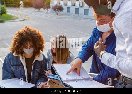 Männliche und weibliche Schüler tragen Sicherheitsmaske während der Diskussion in Universitätsgelände Stockfoto