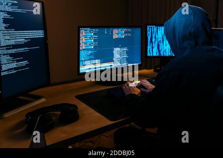 Hacker tragen Kapuzenpullover und arbeiten am Computer, während sie im Büro sitzen Stockfoto