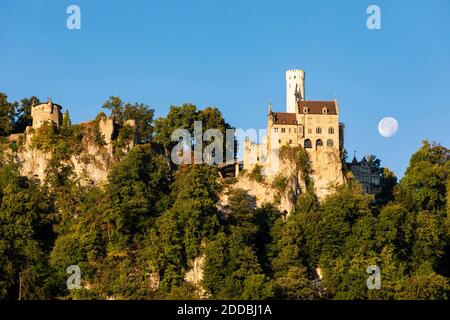 Deutschland, Baden-Württemberg, Schloss Lichtenstein in der Abenddämmerung mit aufsteigendem Mond im Hintergrund Stockfoto