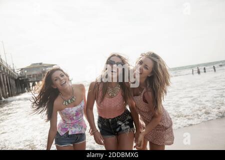 Fröhliche junge Freundinnen genießen Wochenende am Strand gegen klar Himmel Stockfoto