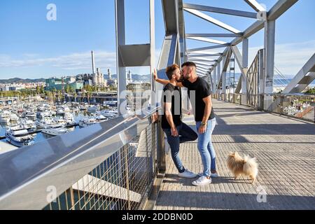 Liebevoll Gay paar küssen auf Fußgängerbrücke während sonnigen Tag Stockfoto