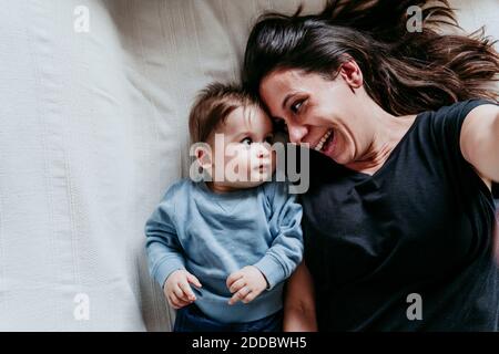 Lächelnde Mutter und Sohn machen Selfie, während sie sich darauf legen Bett zu Hause Stockfoto