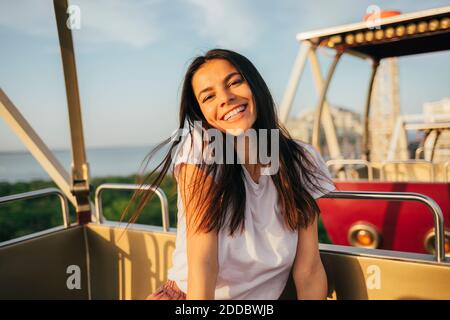 Fröhliche junge Frau genießen Riesenrad Fahrt gegen den Himmel an Sonnenuntergang Stockfoto