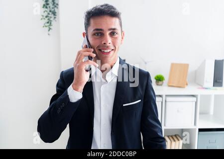 Selbstbewusster junger Geschäftsmann, der im kreativen Büro telefoniert Stockfoto