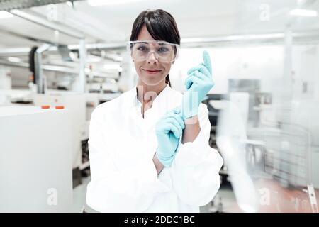 Lächelnde reife Wissenschaftlerin trägt Handschuhe im Labor Stockfoto
