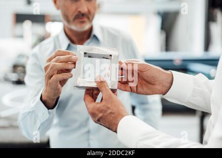 Männliche Ingenieure halten und diskutieren über quadratisch geformtes Metall in Branche Stockfoto