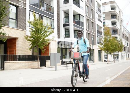 Fröhlicher Mann, der Musik hört, während er mit dem Fahrrad in der Stadt pendelt Stockfoto