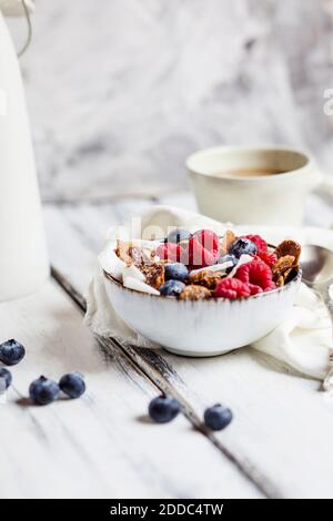 Schüssel mit hausgemachtem Getreide mit Kokosnuss, Himbeeren und Heidelbeeren Stockfoto