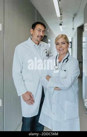 Lächelnder Arzt und Wissenschaftler, der am Klinikkorridor steht Stockfoto
