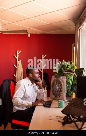 Fokussierter junger Geschäftsmann, der am Computer am Schreibtisch in Coworking arbeitet Büro Stockfoto