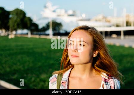 Nachdenkliche Frau, die wegschaut, während sie im öffentlichen Park steht Sonniger Tag Stockfoto