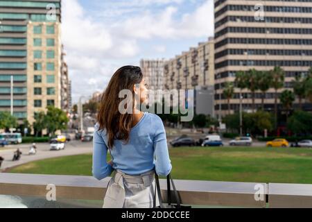 Lächelnde junge Geschäftsfrau, die die Stadt anschaut Stockfoto