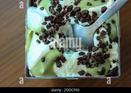 Pistazien-Eis mit geriebener Schokolade, in einem durchsichtigen Plastikbehälter Stockfoto