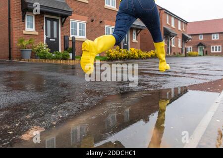 Nahaufnahme einer Frau, die während der Wasserpfütze auf der Straße springt Regenzeit Stockfoto