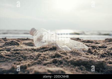 Plastikwasserflasche auf Sand am Strand Stockfoto