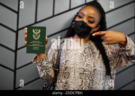 Afrikanische Frau trägt schwarze Gesichtsmaske zeigen Südafrika Pass in der Hand. Coronavirus in Afrika Land, Grenzschließung und Quarantäne, Virusausbruch Stockfoto
