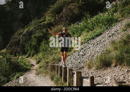 Frau, die an sonnigen Tagen auf Holzpfosten wandert Stockfoto