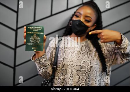 Afrikanische Frau trägt schwarze Gesichtsmaske zeigen Gambia Pass in der Hand. Coronavirus in Afrika Land, Grenze Schließung und Quarantäne, Virus Ausbruch conce Stockfoto