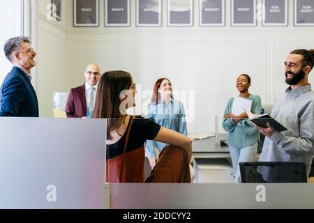 Lächelnde Unternehmer und Unternehmerinnen diskutieren Strategien am Arbeitsplatz Stockfoto